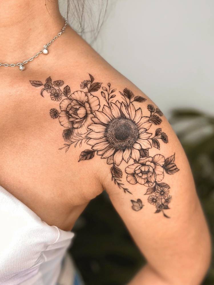 Mulher de pele clara e cropped branco com tatuagem de girassol sombreada no ombro