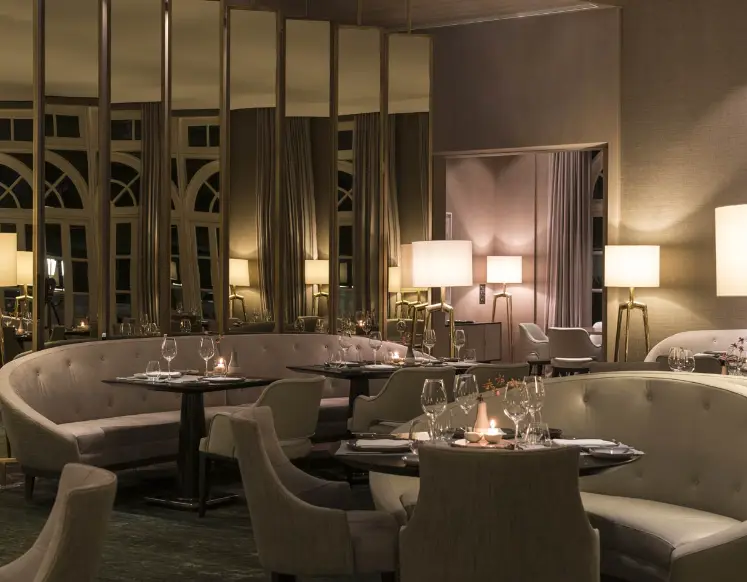 Sala de jantar com sofás claros e mesas com taças. Tangerá Jean-Georges - Restaurantes icônicos em SP