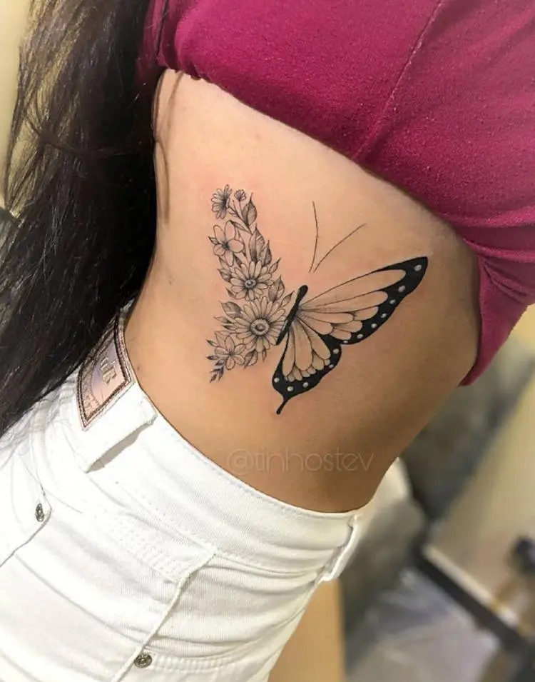 Tatuagem de borboleta grande na costela, sendo metade dela flores 
