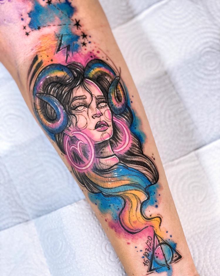 Tatuagem de signo no estilo Aquarela em braço: deusa com chifres e brincos de argola signo de áries
