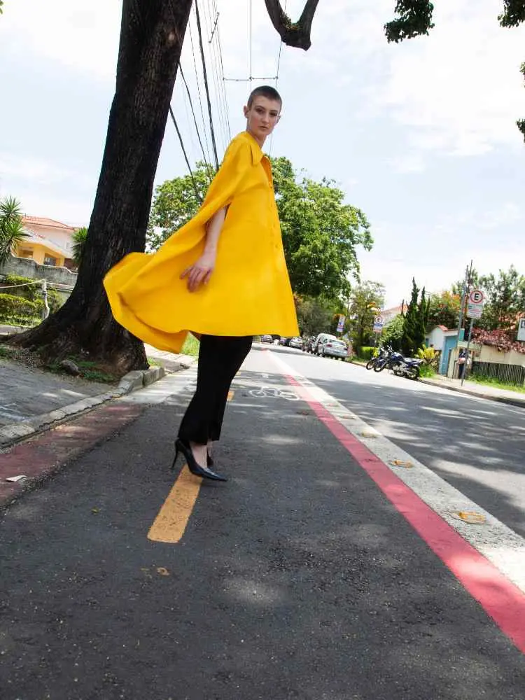 Mulher não-modelo com mais de 30 anos em ensaio fotográfico, usando blazer amarelo, calça preta e scarpin preto
