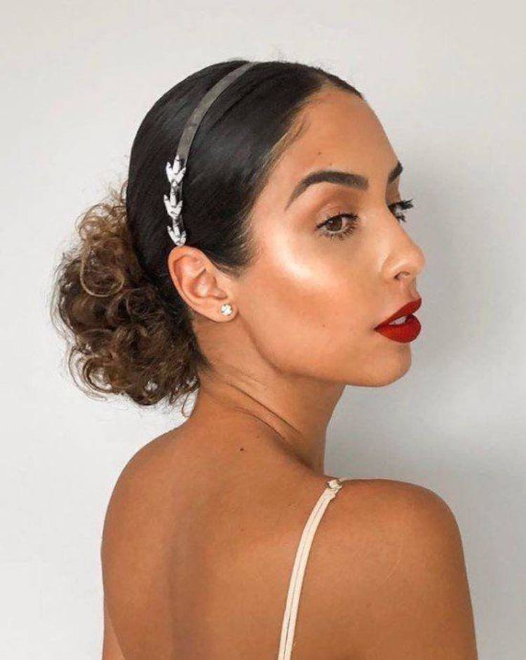 Mulher de pele morena com coque baixo cacheado e tiara 