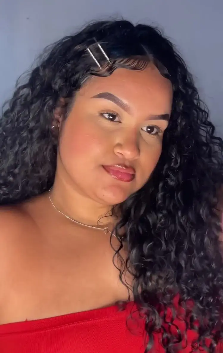 Mulher de pele morena com cabelo preto cacheado com presilhas prateadas