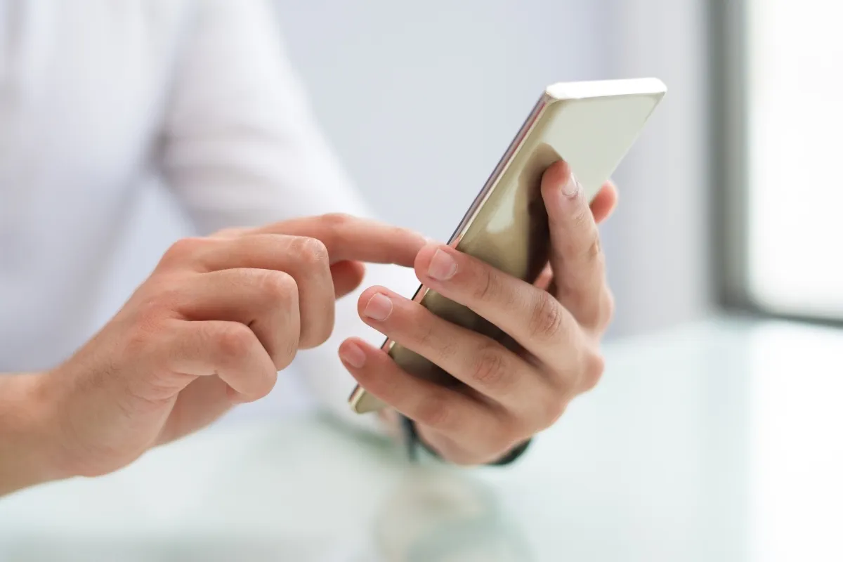Foto de mão mexendo em celular com número de WhatsApp de outro país