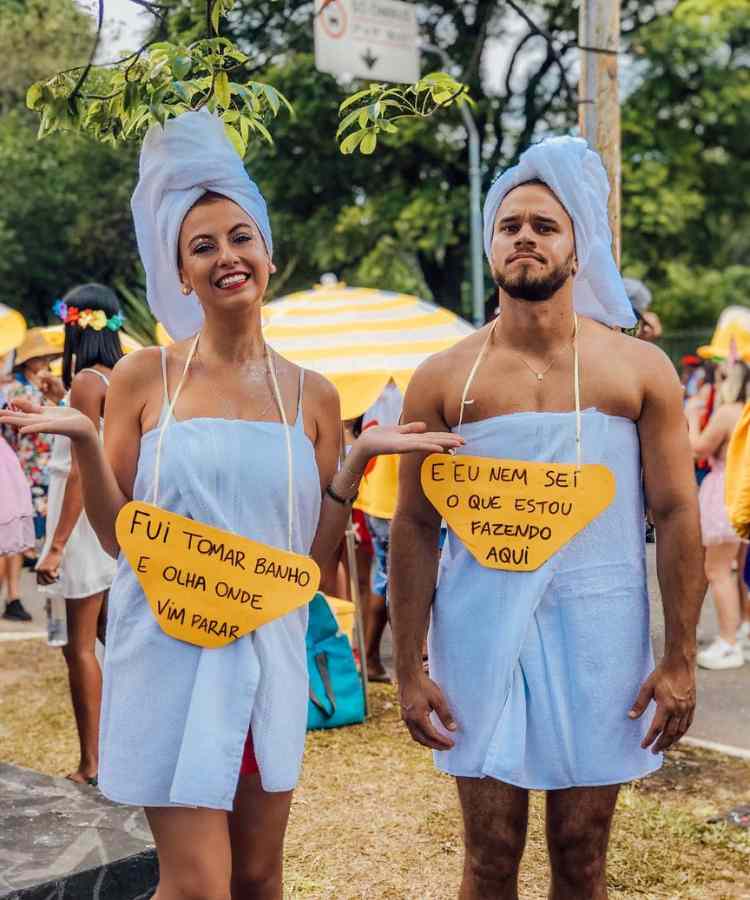 Traje de Dia das Bruxas para namorados: Perdidos na rota do banho. Ambos usam toalha na cabeça e no corpo, além de plaquinhas amarelas 