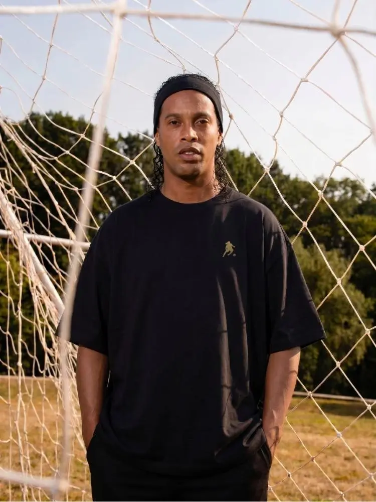 Ronaldinho Gaúcho usando camiseta preta oversized de sua marca de roupas