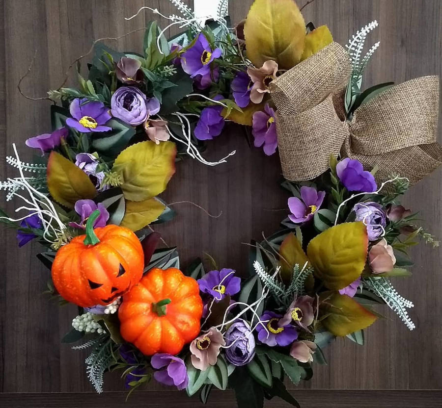 Guirlanda de Halloween com flores roxas, mini abóboras, laços e folhas.