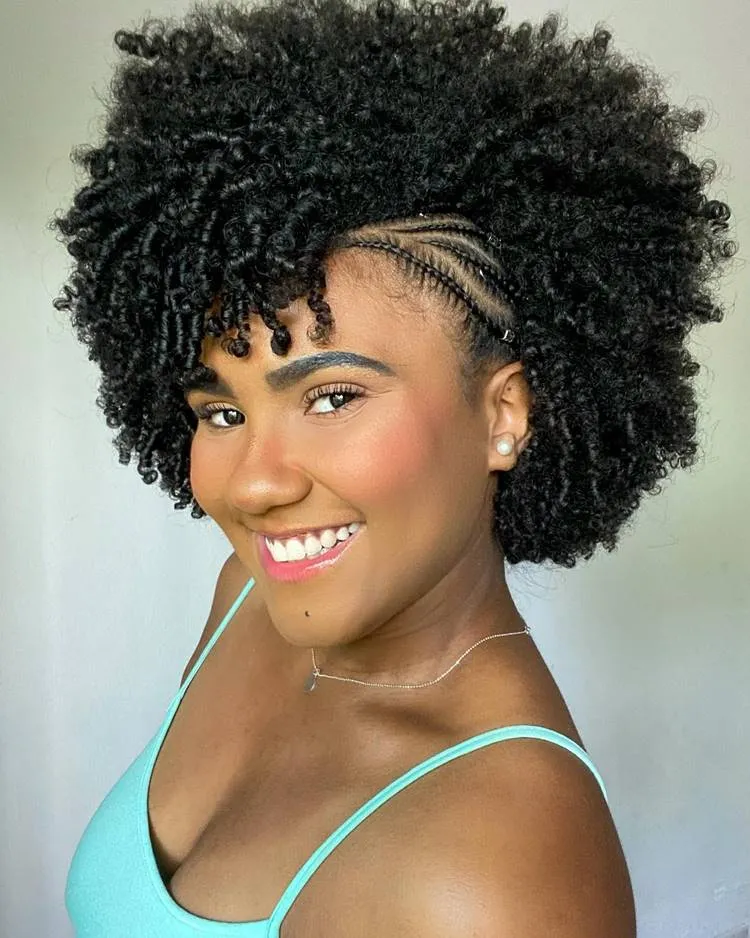 Trança nagô lateral simples em cabelo crespo curto. Mulher sorri com make leve e blusa de alcinha verde água
