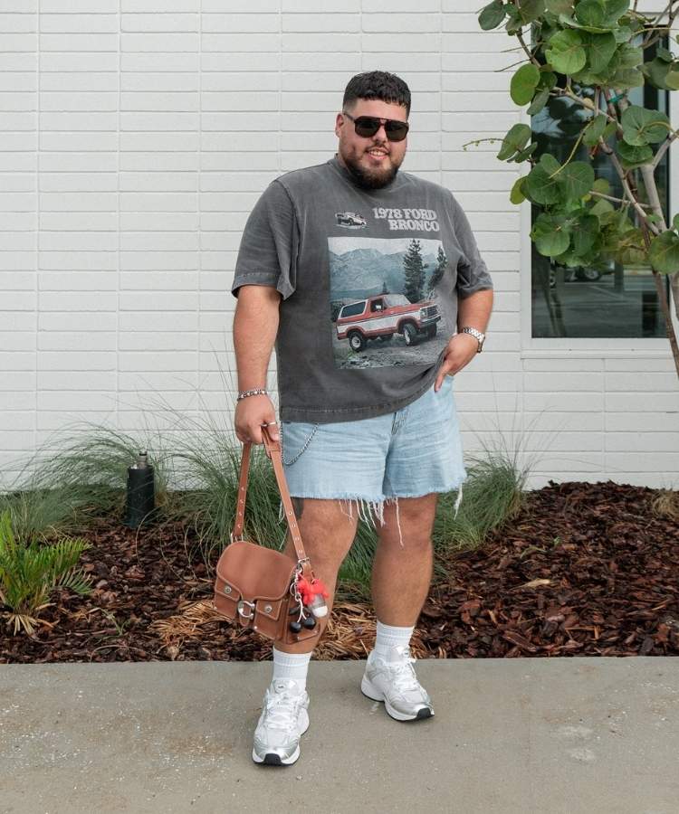 Influencer plus size usando camiseta gráfica com modelagem oversized e shorts jeans desfiado com tênis branco