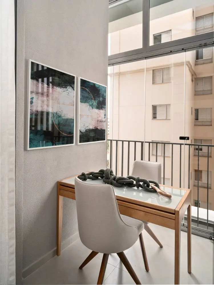 Sacada de parede cinza com quadros, mesa com duas cadeiras e decoração