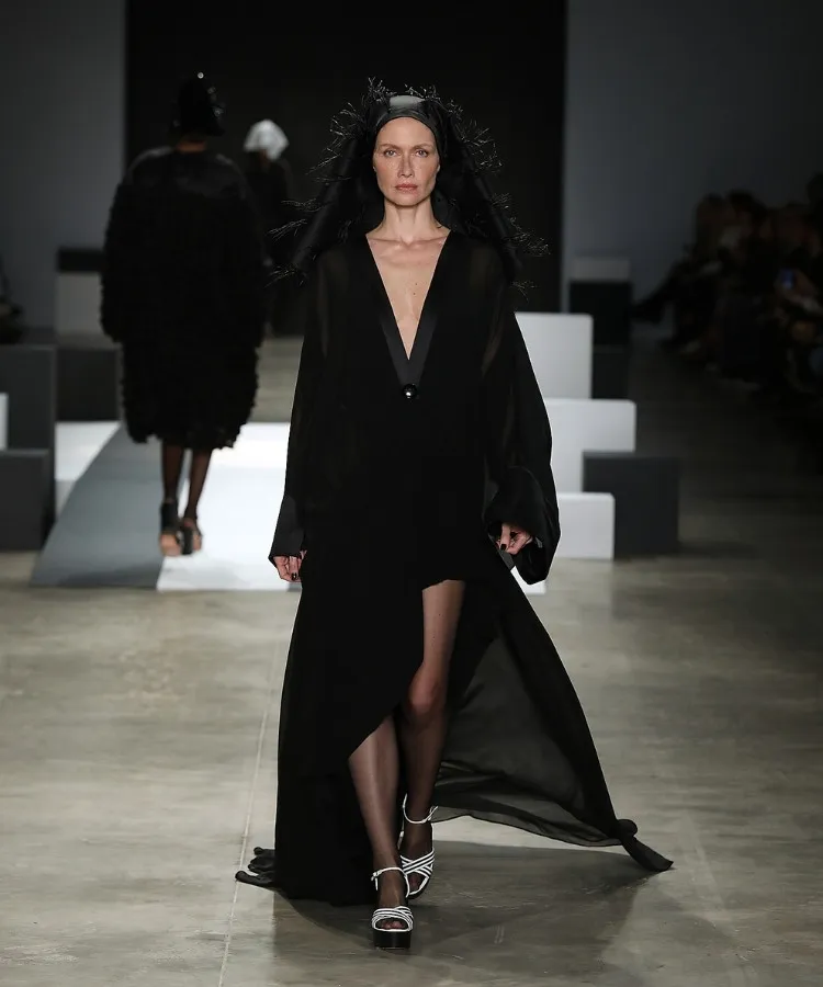 Foto de modelo na passarela usando vestido longo preto