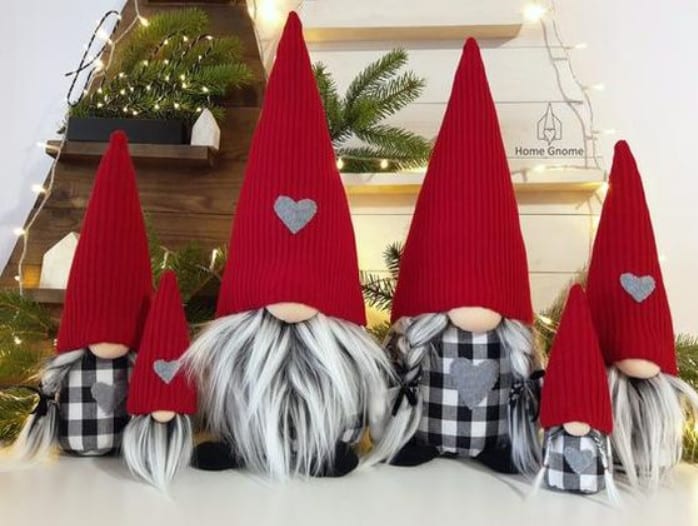 Foto de duendes de diferentes tamanhos, usando roupa xadrez branca e preta e gorro vermelho
