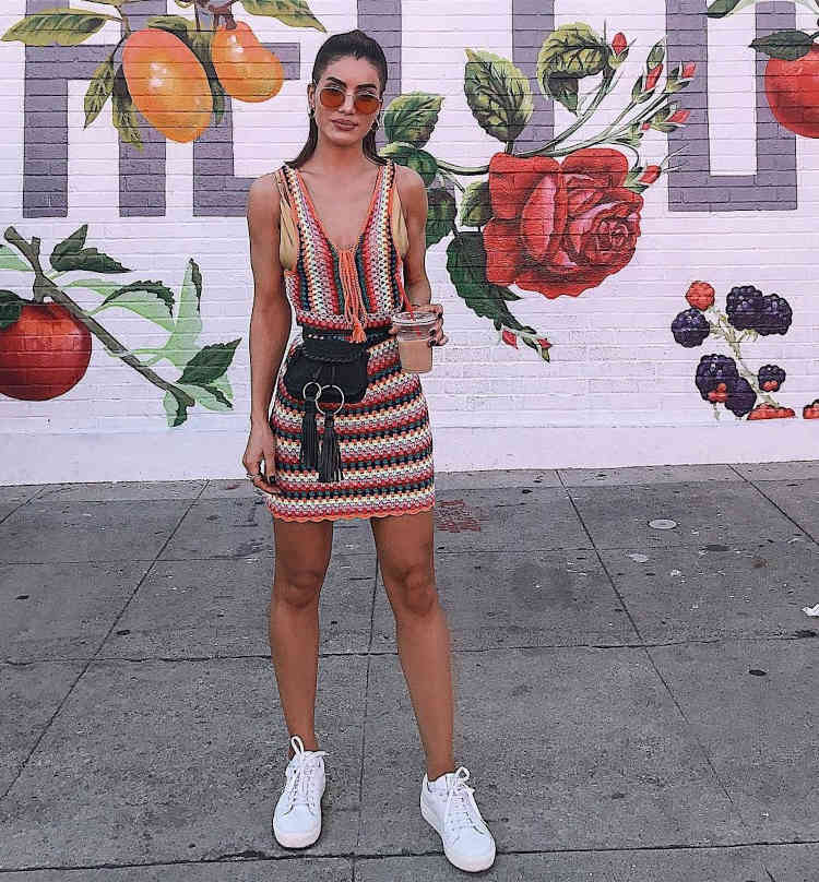 Mulher de pele clara usando conjunto de crochê colorido e tênis branco