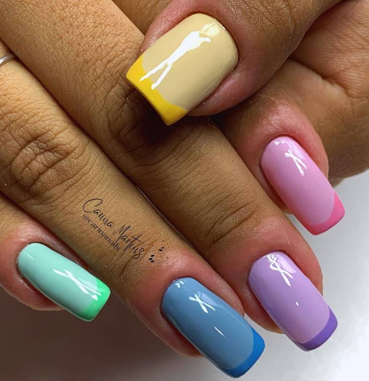 Mão com unhas decoradas coloridas: Polegar: amarelo pastel com francesinha amarela Indicador: rosa pastel com francinha pink Médio: lilás com francesinha roxa Anelar: azul pastel com francesinha azul céu Mínimo verde pastel com francesinha verde escuro