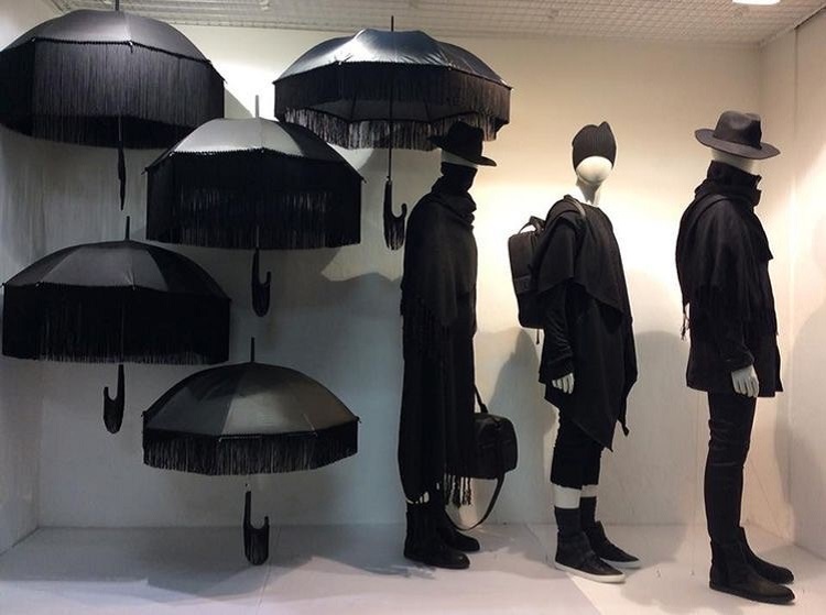 Vitrine de loja de roupa com manequins e guarda-chuvas pretos