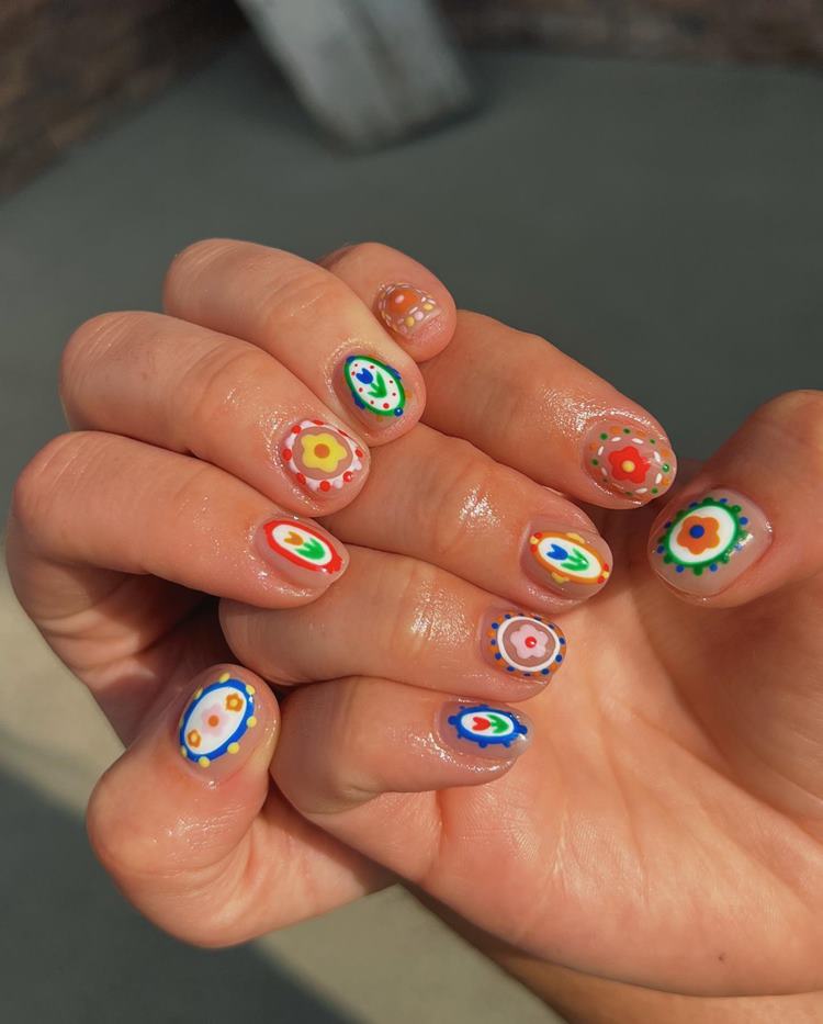 Nail art carnavalesca colorida, cada unha decorada com uma flor diferente