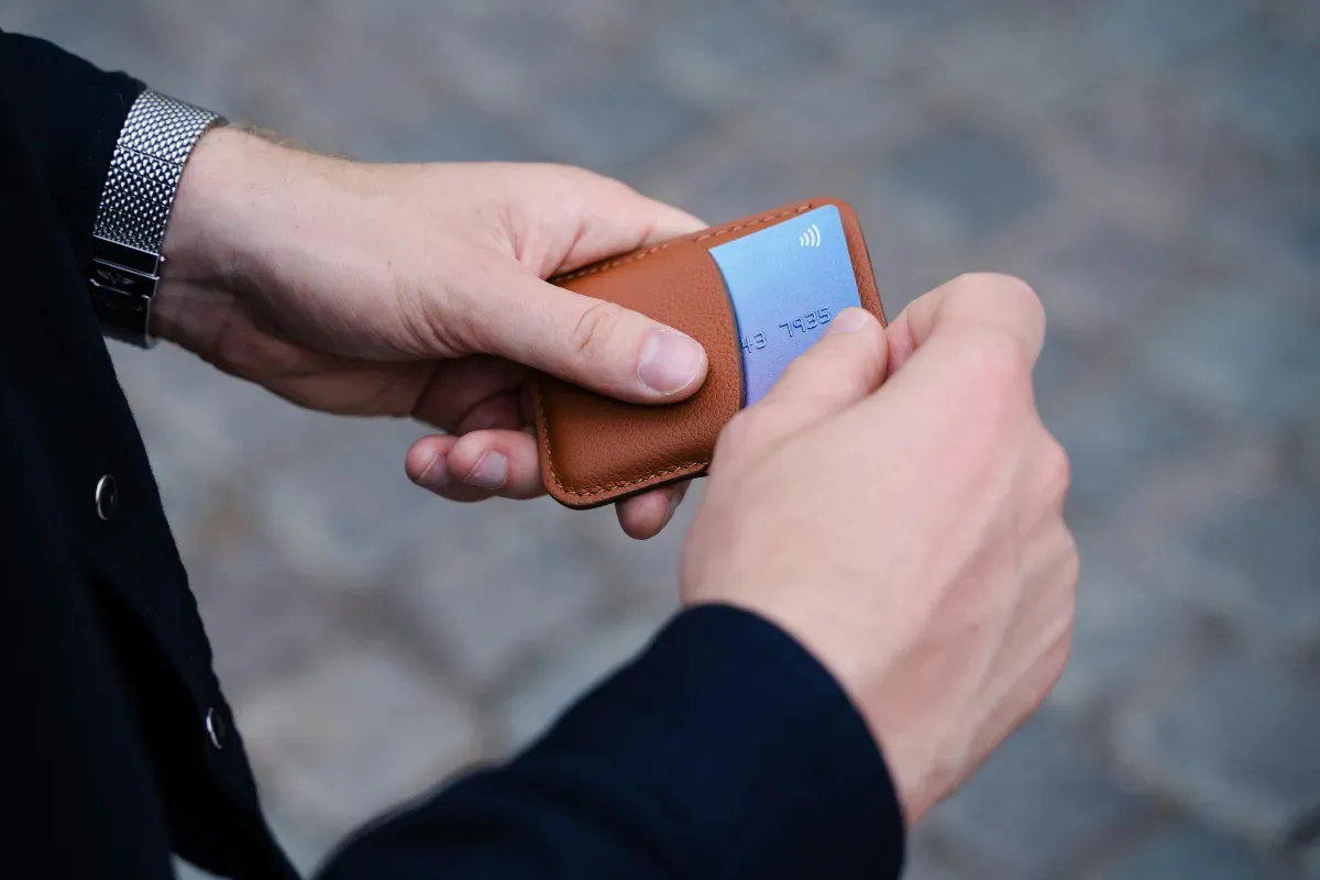 Pessoa segura smartphone e cartão durante uma solicitação financeira