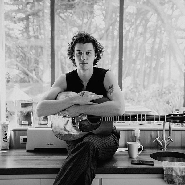 Em uma foto preto e branco, Shawn Mendes posa com um violão, em sua casa famosos signo leão: Shawn Mendes