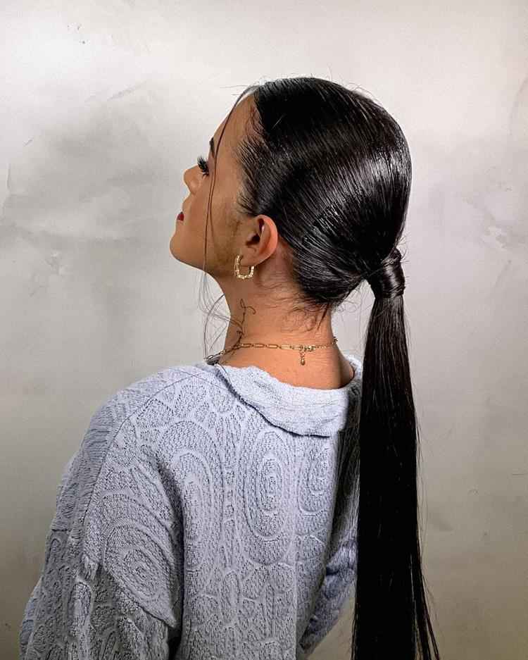 mulher  de pele clara com cabelo preto liso em rabo de cavalo baixo