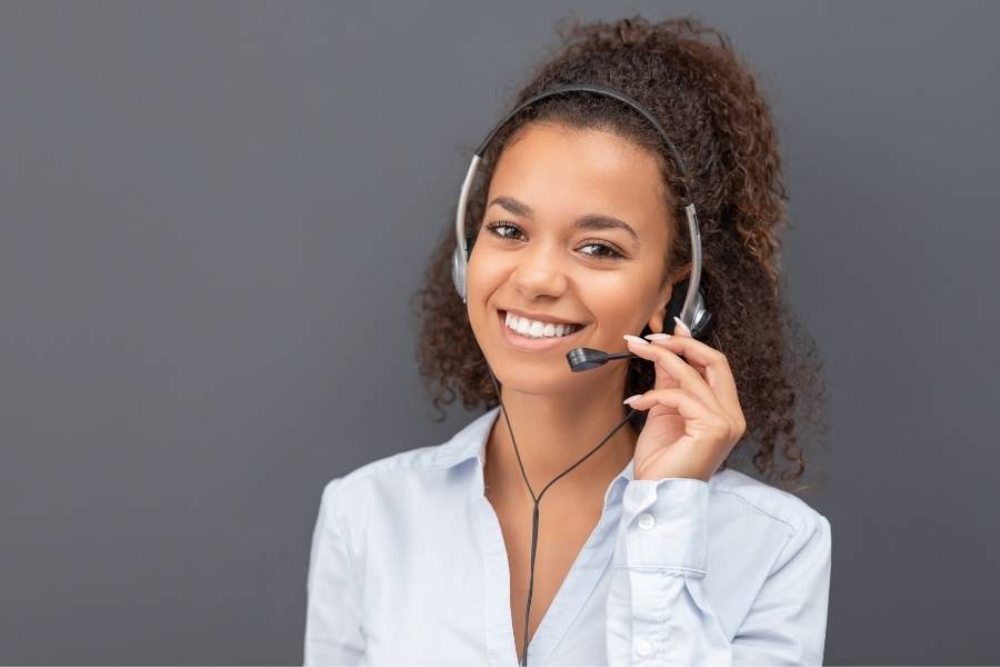 Mulher atendente sorrindo com fone com microfone.