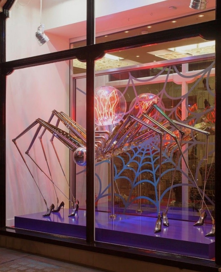 Decoração de Halloween em vitrine de sapatos, com aranha prateada calçando saltos 