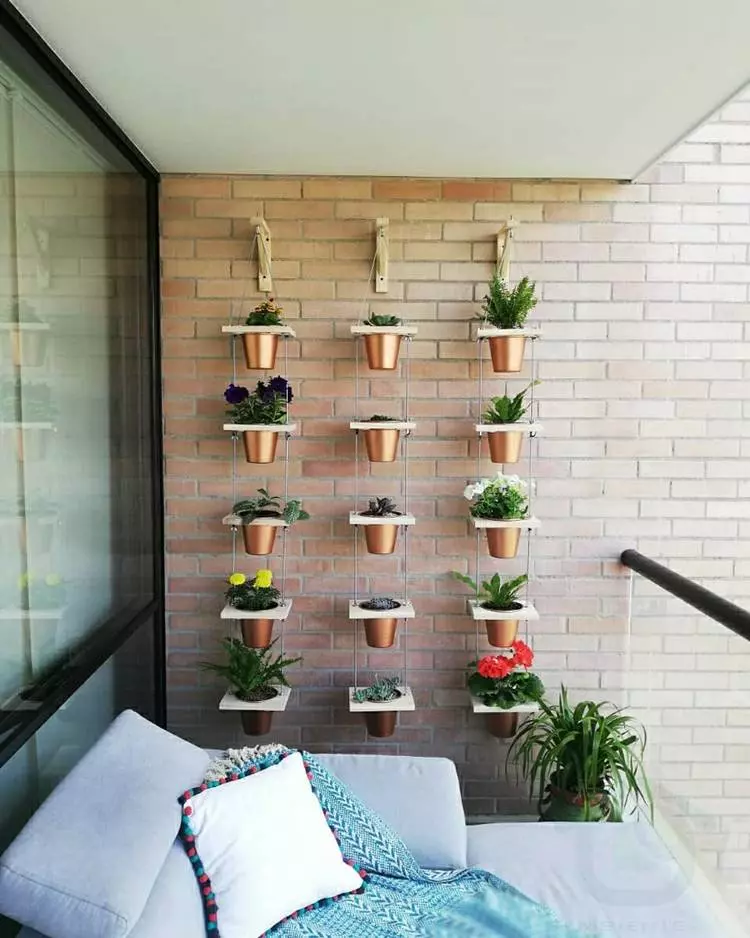 Decoração de plantas em vasinhos pendurados em parede de tijolinhos na fachada de apartamento, com estofado