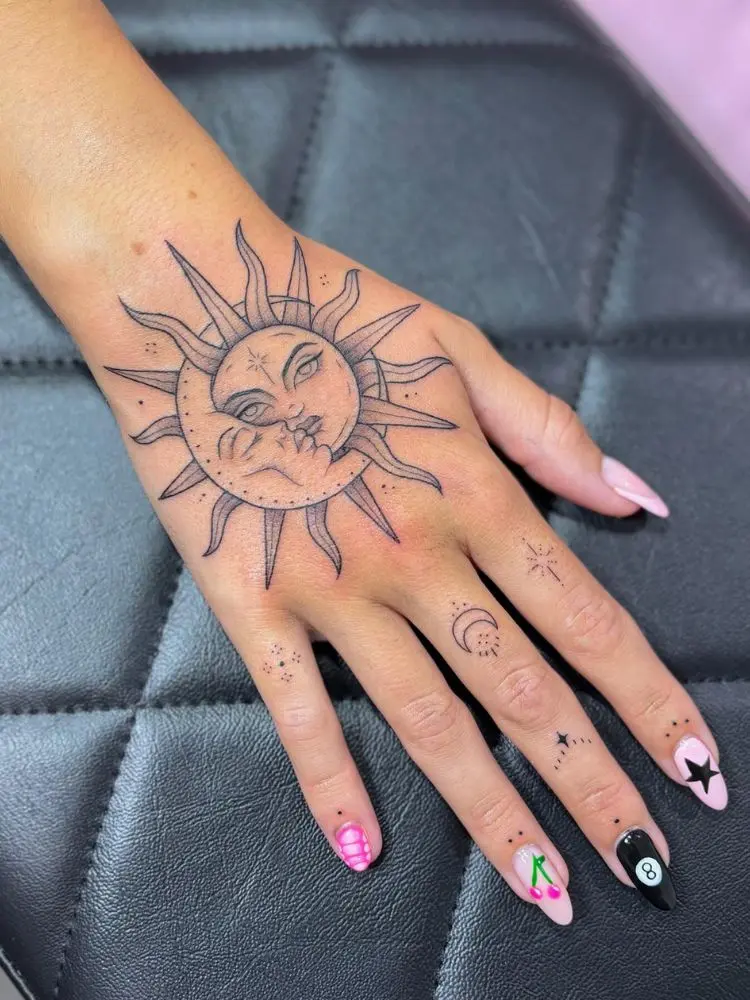 Mão com tatuagem sombreada da união de sol e lua 