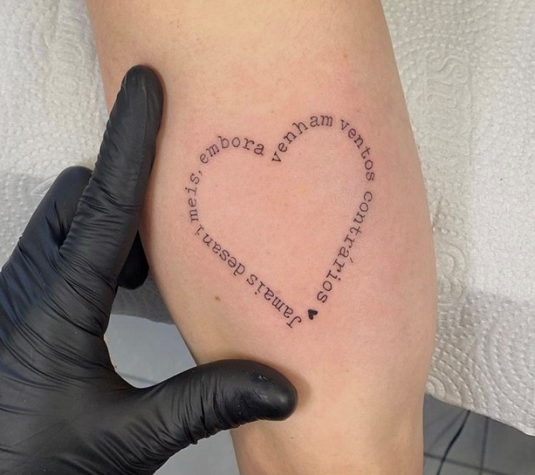Pessoa de pele clara com tatuagem de frase no formato de coração 