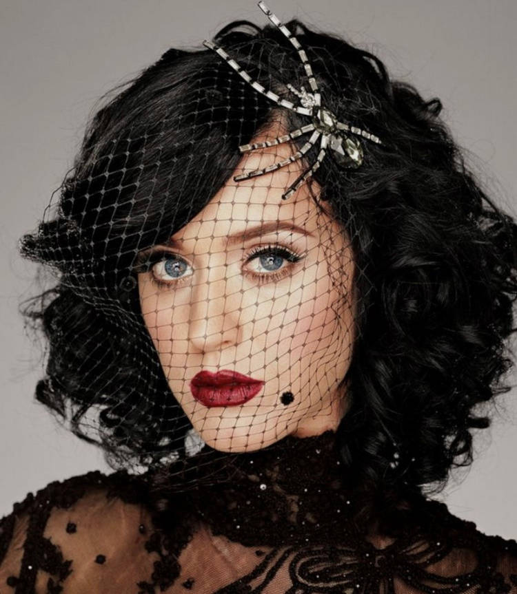 Katy Perry usando fantasia de halloween, com voilette preto e aranha de pedras 