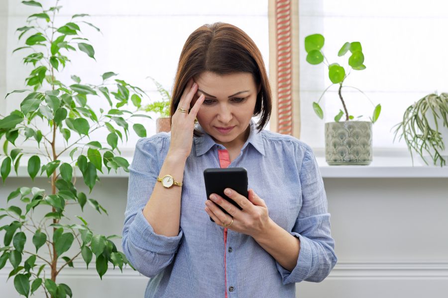 Mulher segurando celular com cara de preocupada, vendo aplicativo de relacionamento