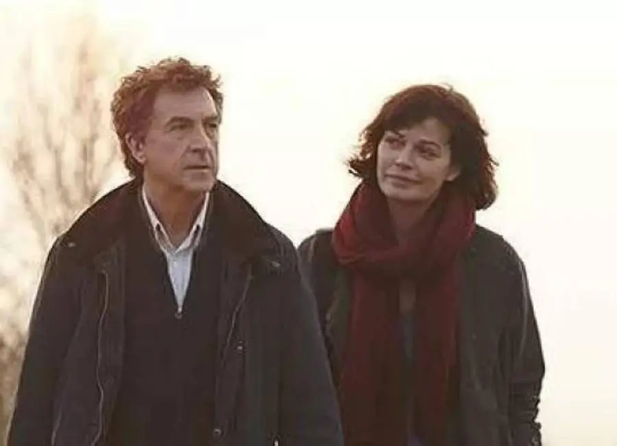 Atores do filme "Insubstituível" caminhando em local frio com árvores secas. 
