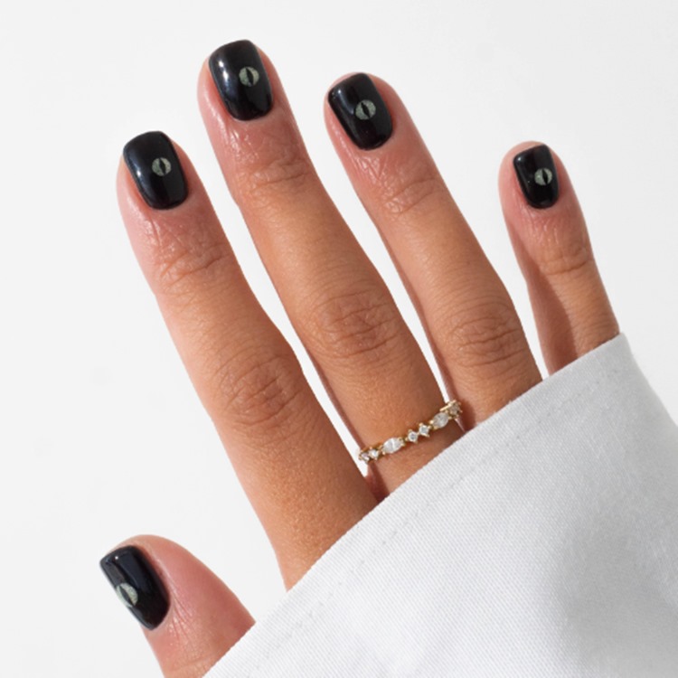 Mão com unhas curtas quadradas decoradas de olho de gato preto nas cores preto e glitter esverdeado