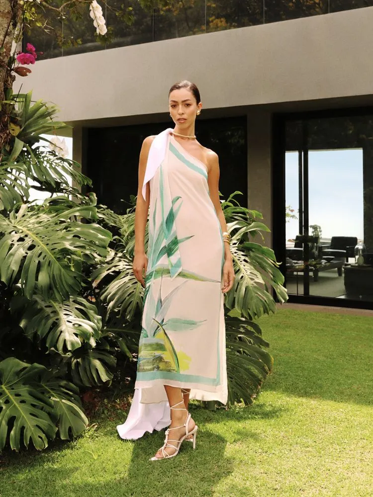 Uma mulher posa em um jardim, ela usa um vestido branco com estampas florais da coleção dias dourados da DIMY