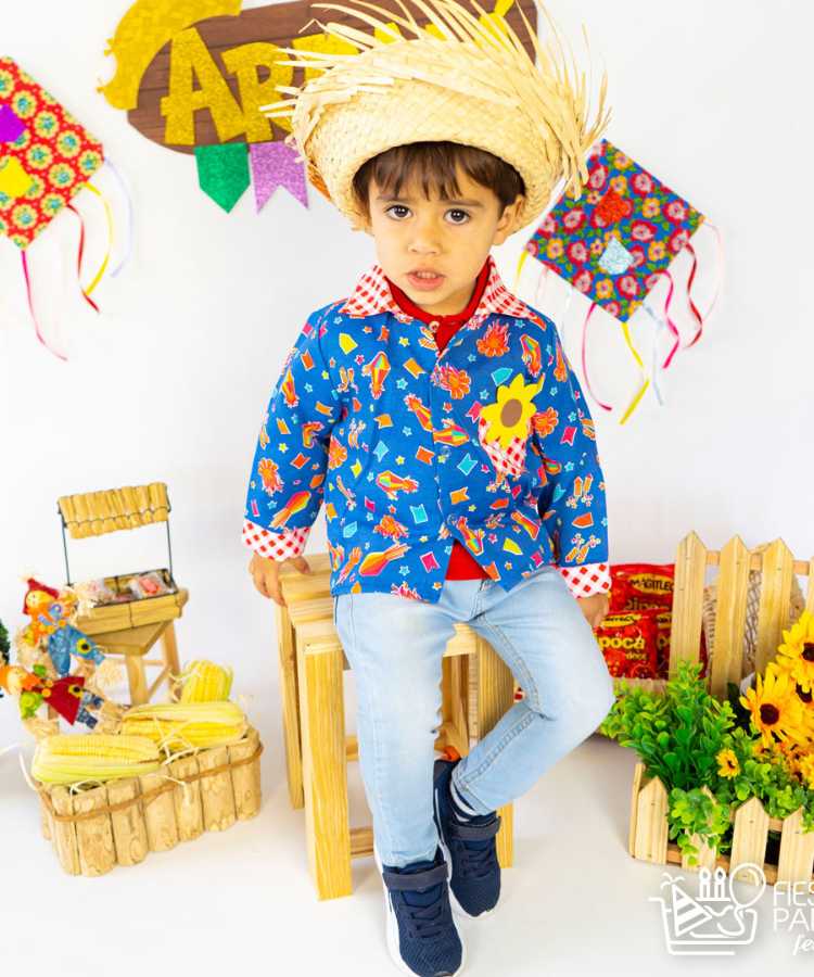 Menino com roupinha de quadrilha (blusa colorida com girassóis e calça jeans) e chapéu de palha