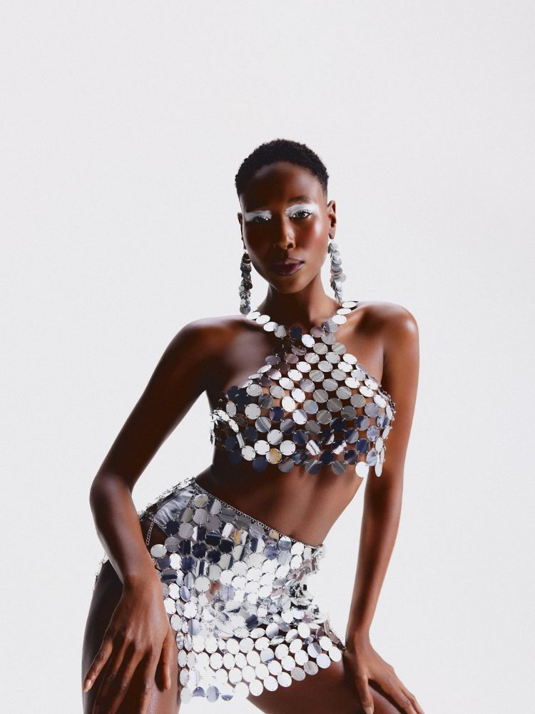 Mulher de pele negra usando cropped e saia prateados 