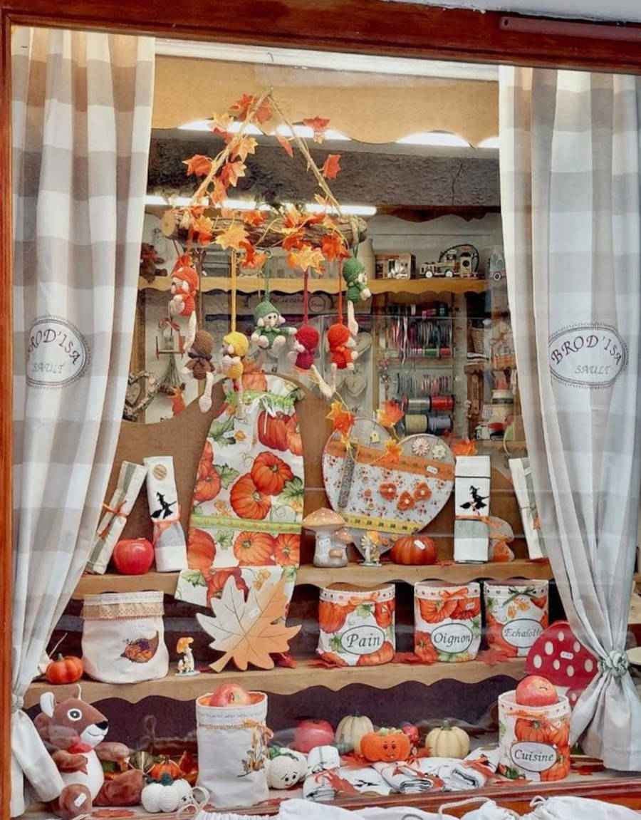 Loja de decoração de casa com enfeites de abóbora na frente e cortinas xadrez
