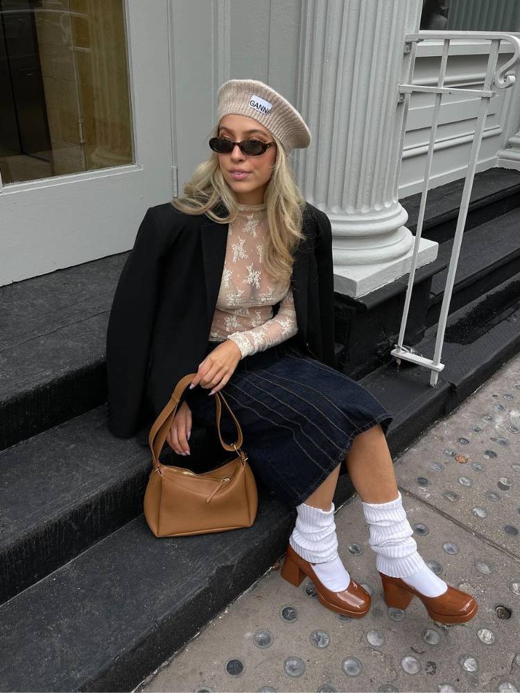 mulher usando boina, blusa de renda, blazer preto, saia jeans longa, polainas brancas e sapato Mary Jane de salto marrom de verniz