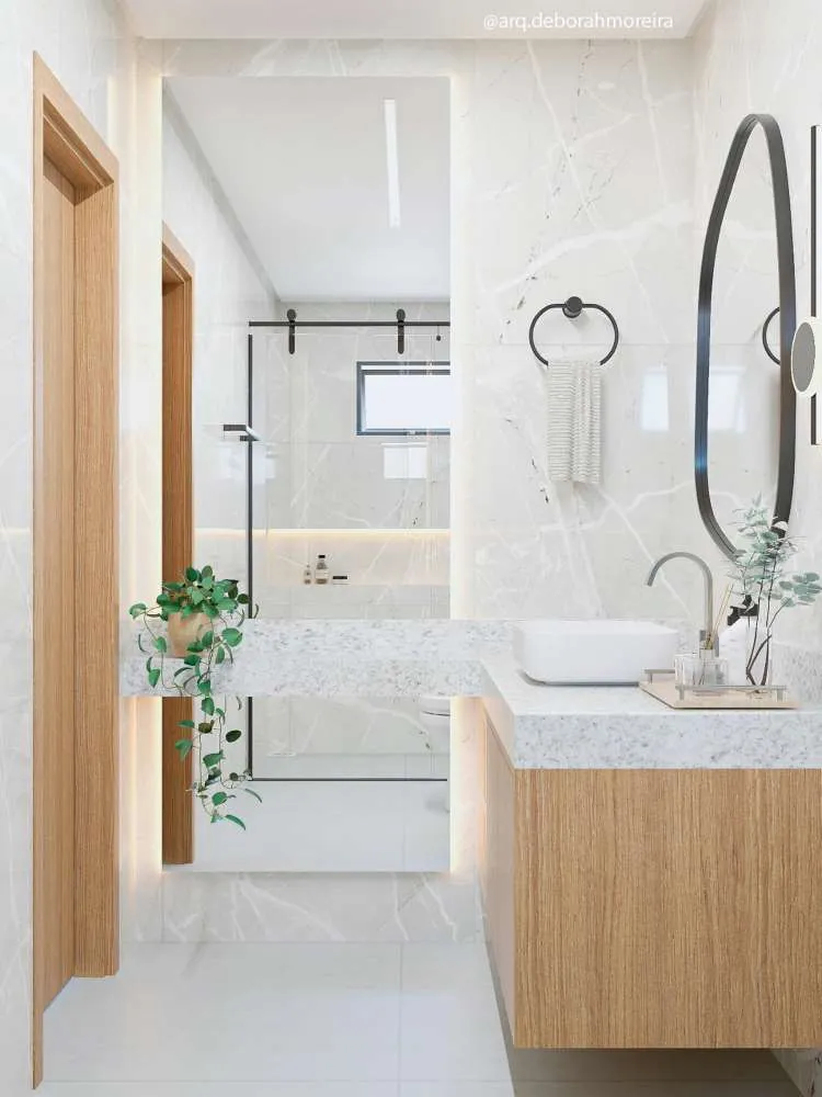 Banheiro branco e em madeira com box de vidro, espelho e vasinho com jiboia pendente.