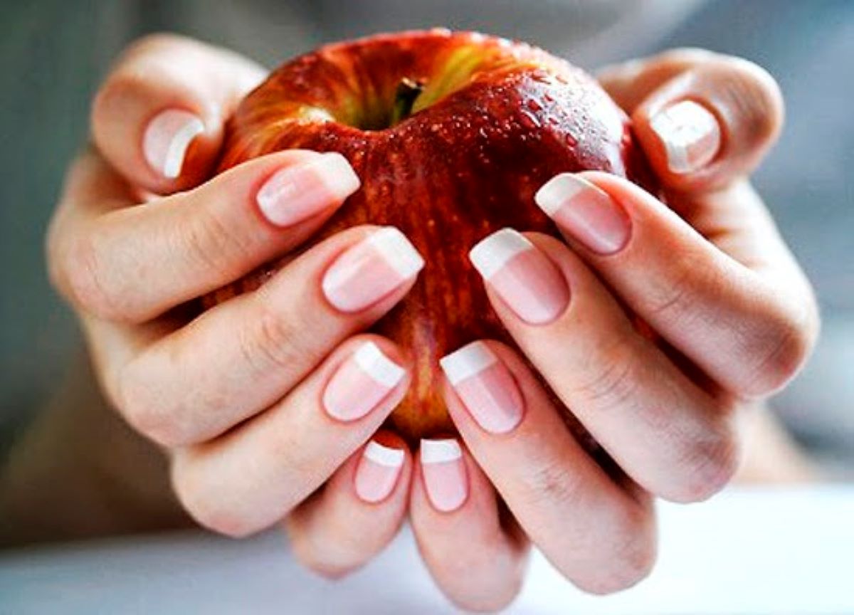 Mãos segurando maçã Mãos segurando uma maçã com foco para as unhas saudáveis