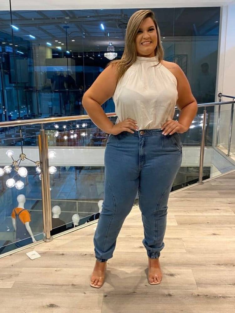 Mulher de pele clara de blusa branca e calça jeans jogger