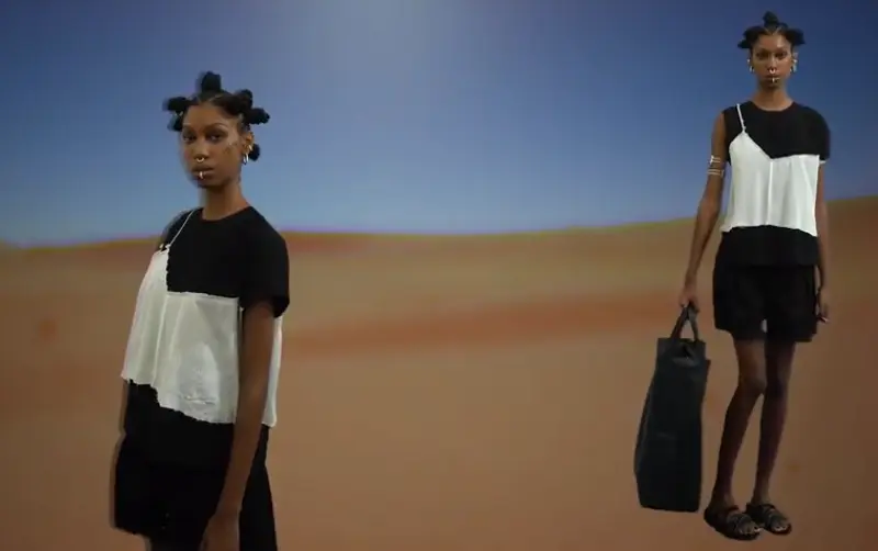 SPFW: A esquerda modelo de lado e a direita de frente vestindo blusa preta com recorte sobreposto branco e short preto.