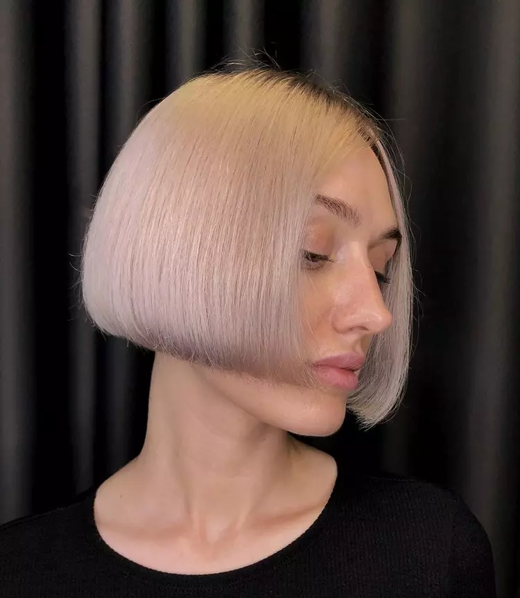 Mulher com corte de cabelo curto platinado Box Bob, usando blusa preta