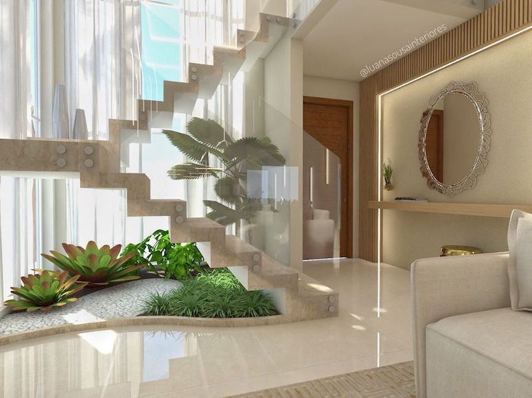 Plantas baixas em jardim de inverno sobre escada de mármore entre sala de estar com sofá bege e hall com espelho 