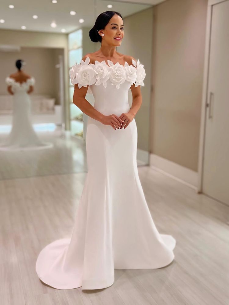 Mulher de pele clara usando vestido de noiva reto, com flores 3D de ombro a ombro 