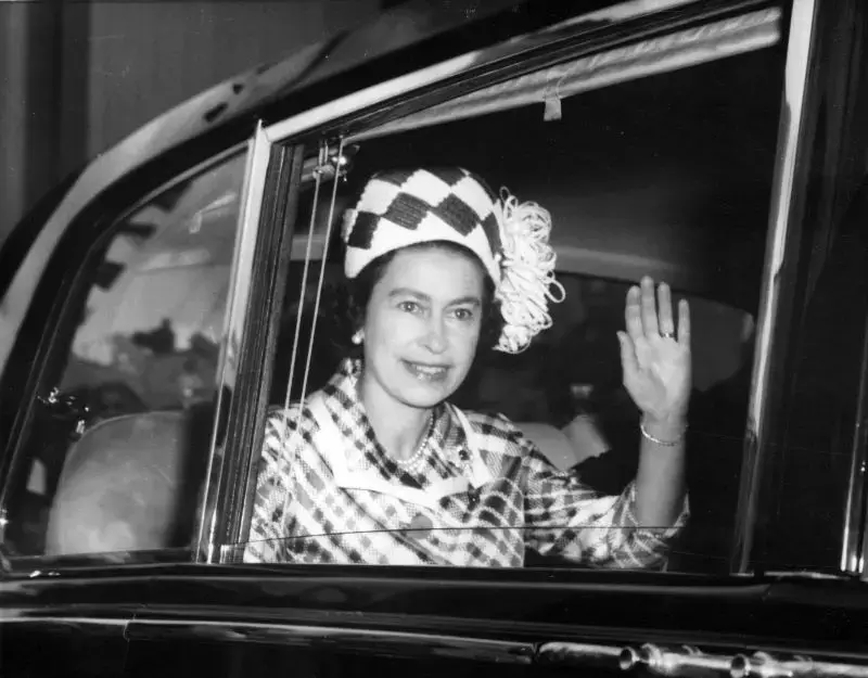 A rainha da Inglaterra Elizabeth II acenando de dentro de um carro 