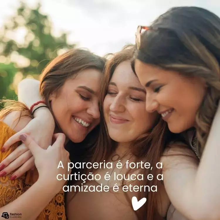 Imagem de três amigas se abraçando, todas de pele e cabelos claros, sorrindo com o céu e árvore ao fundo. Abaixo, há a frase "A parceria é forte, a curtição é louca e a amizade é eterna"
