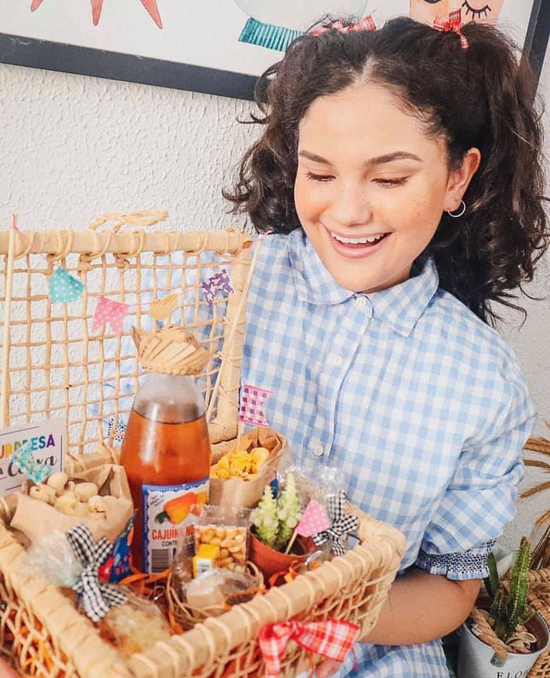 Menina com traje junino segura cesta de festa Junina delivery - Com várias cominhas tradicionais de São João