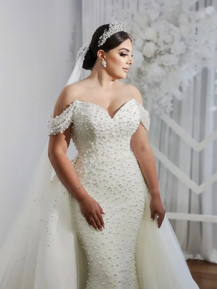 Mulher de pele clara usando vestido corset com alças caídas bordado em pérola e véu