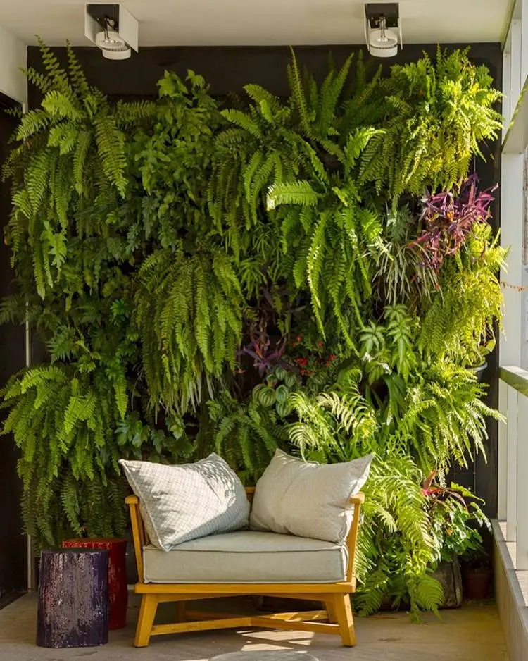 Parede verde natural em fundo preto com poltrona com duas almofadas