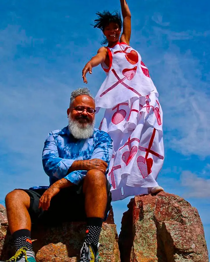 Ronaldo fraga, com modelo Suyane Moreira apoiados em uma pedra.